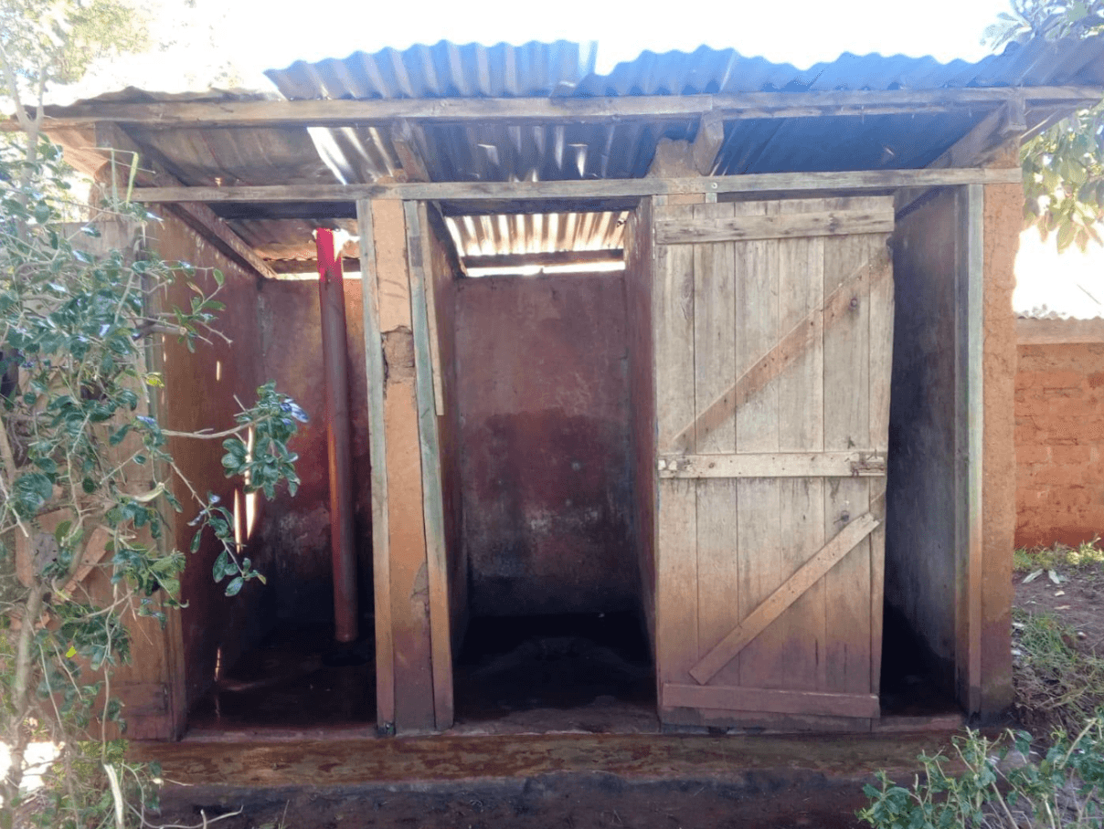 Existing wooden school toilet stalls with a corrugated metal roof